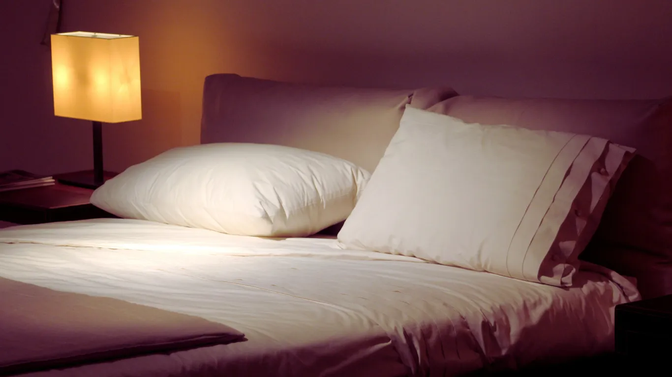 Serene bedroom scene with dim lighting and comfortable bedding